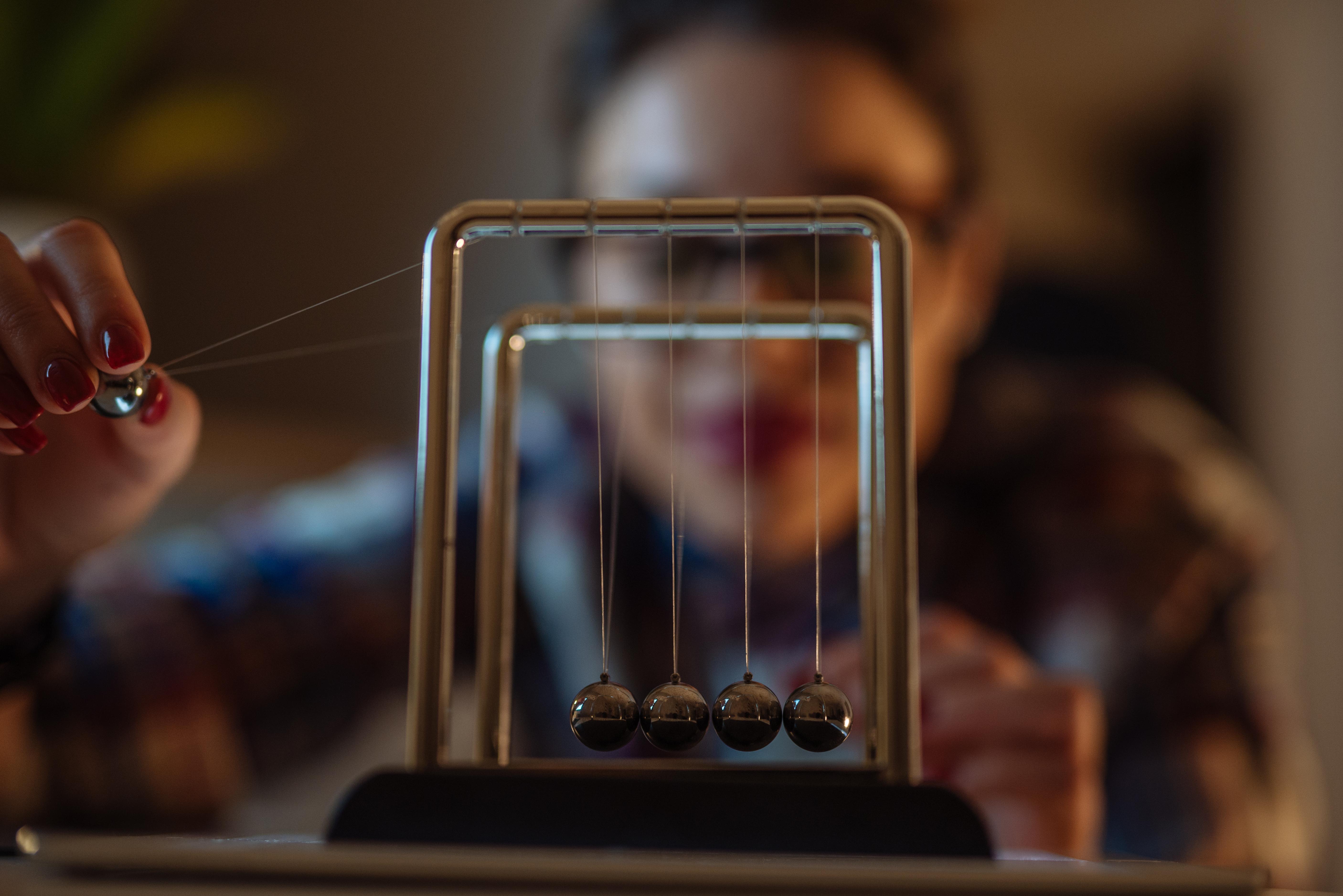 A woman playing with a Newton's Cradle